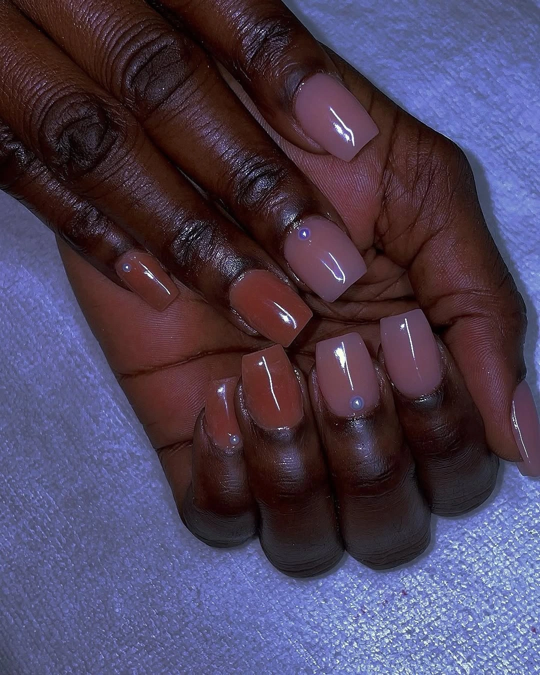 Short tonal nude and rust nails with pearl accents