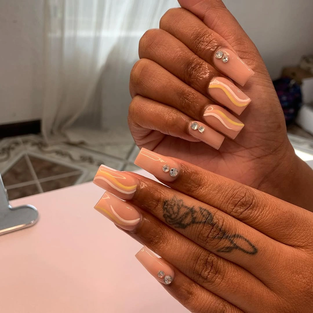 Nude square nails with yellow waves and gems