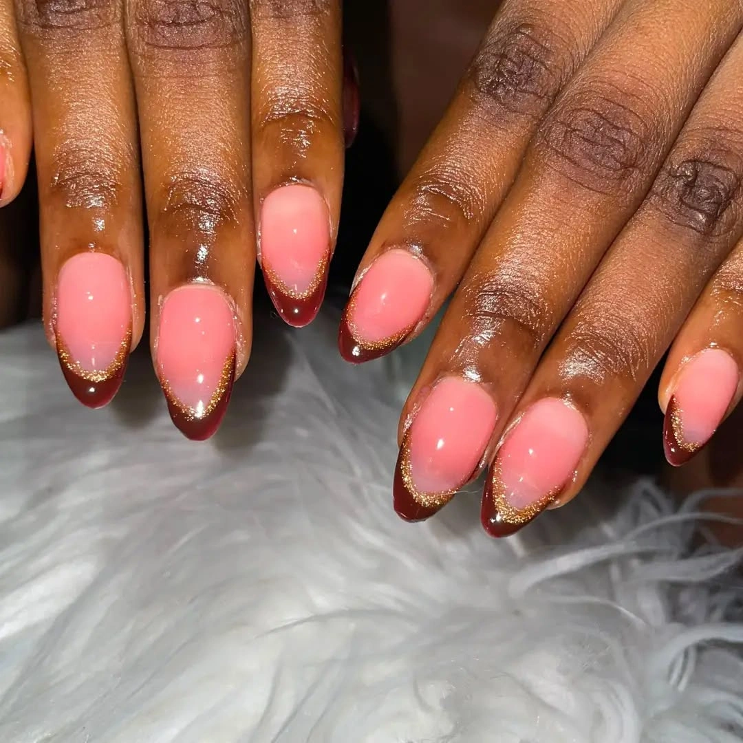 Burgundy almond French tips with gold glitter borders