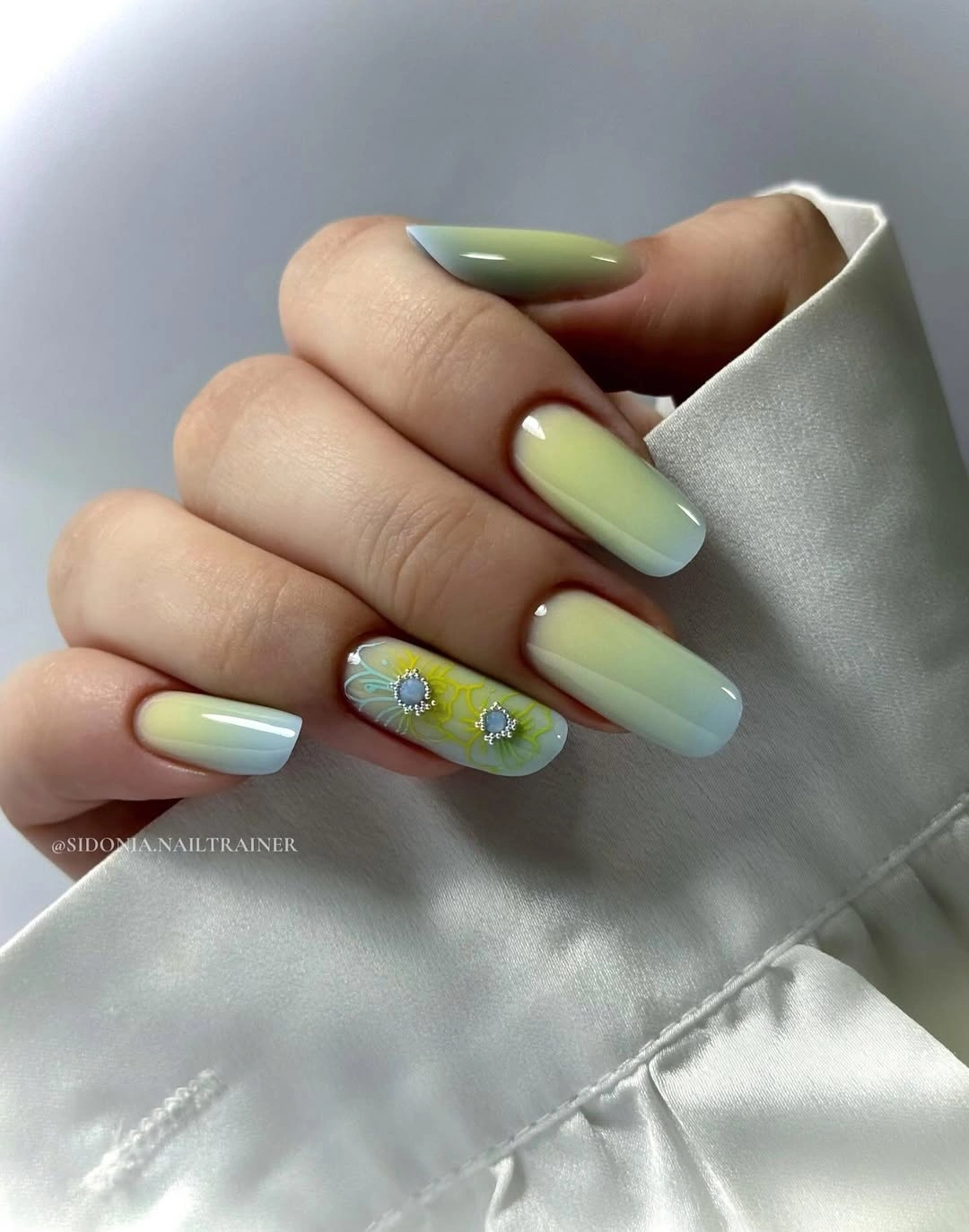Pale yellow green almond nails with blue floral details