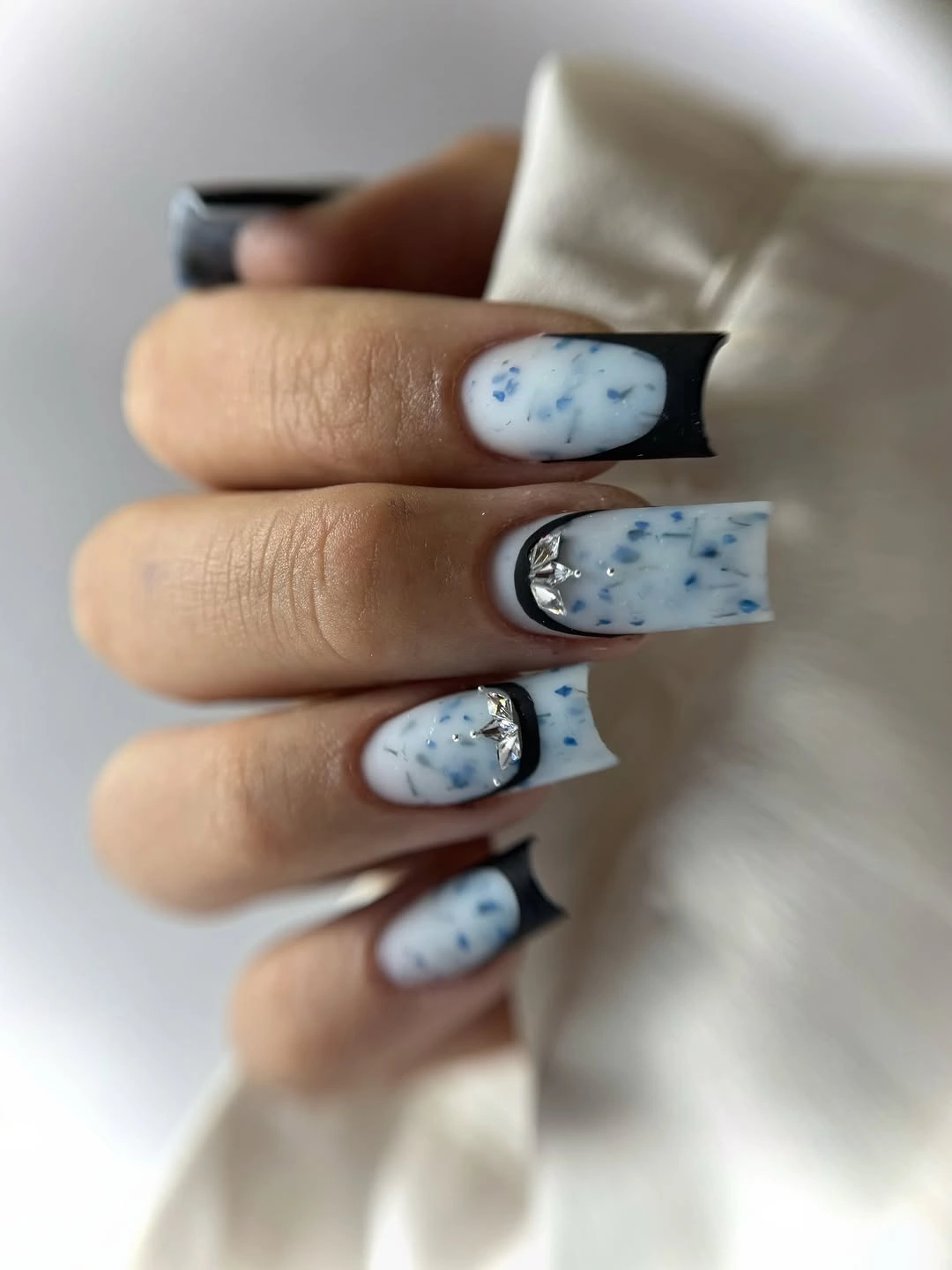 Long square milky nails with blue marbling and black edges