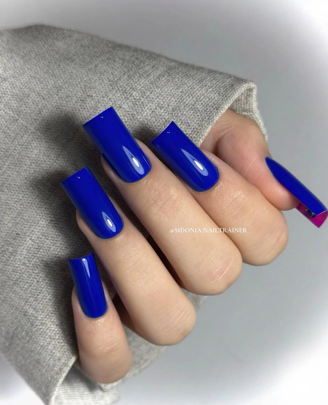 Long square nails in glossy cobalt blue with one pink edge