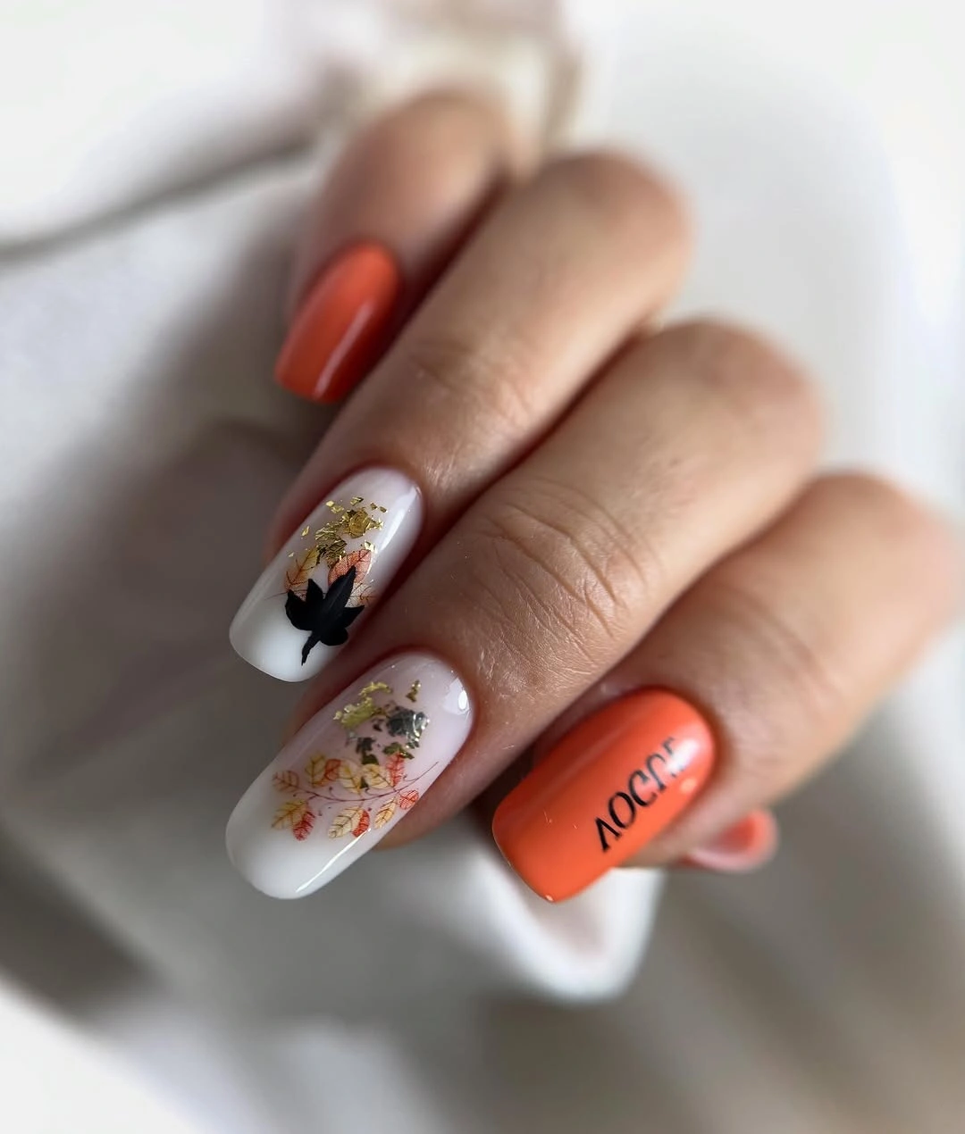 Orange solid nails with white floral illustrated accents