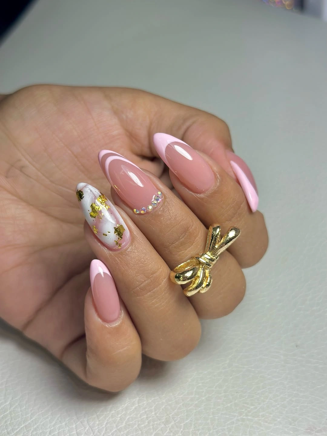Pink almond nails with white curves gold flecks and crystals