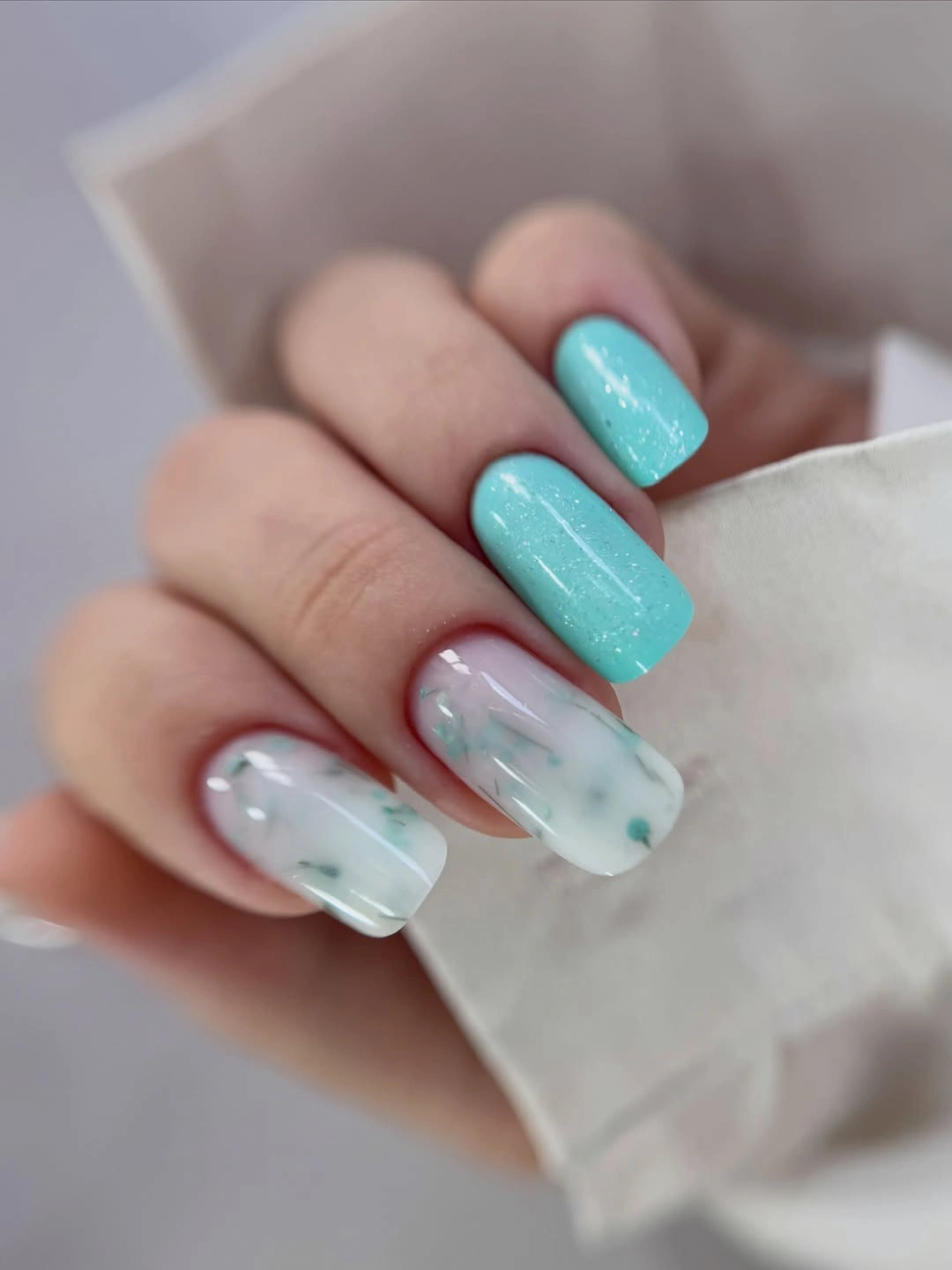 Turquoise rounded nails with milky marbled accent nails