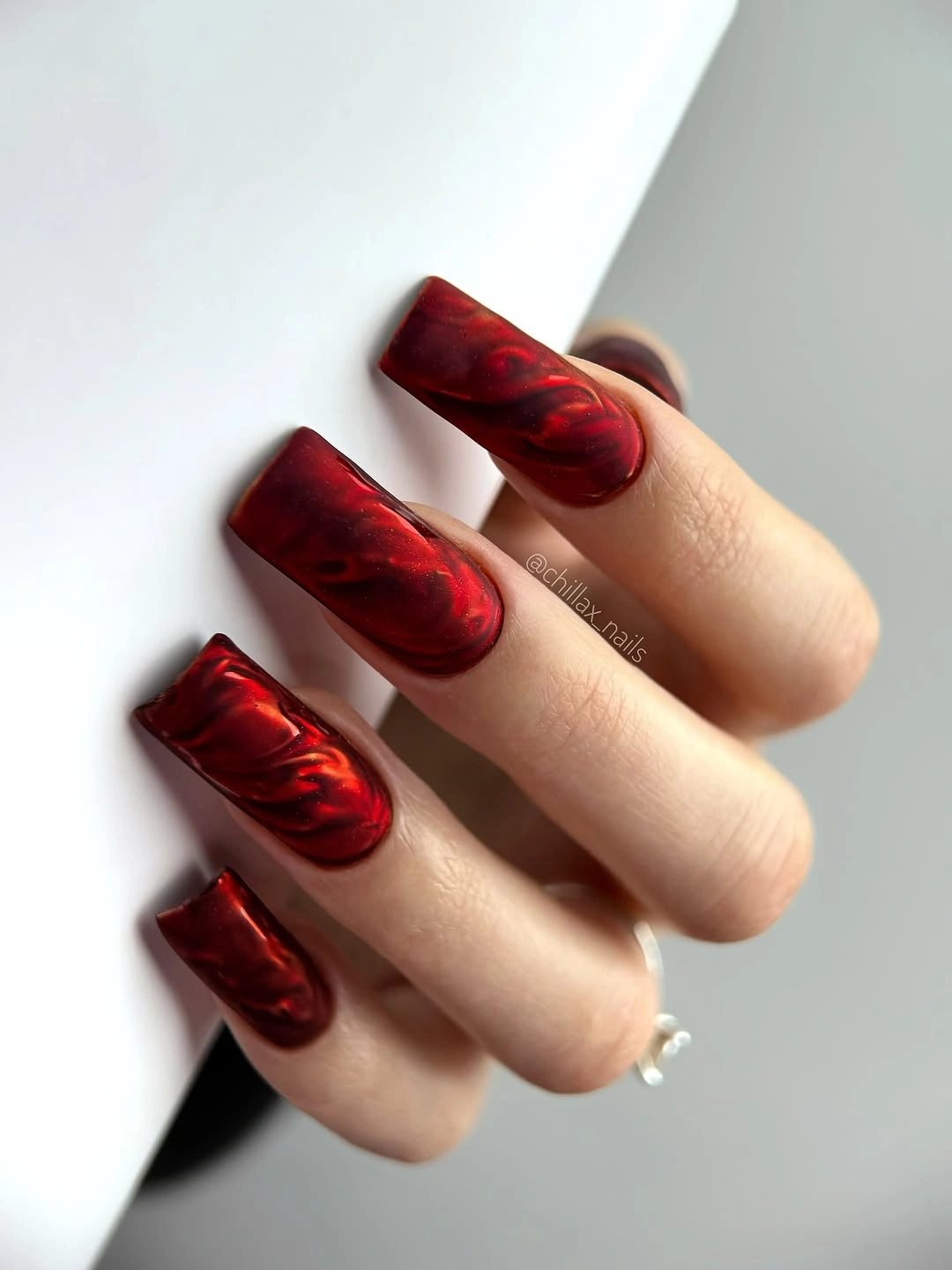 glossy dark red square nails with layered curved marbling