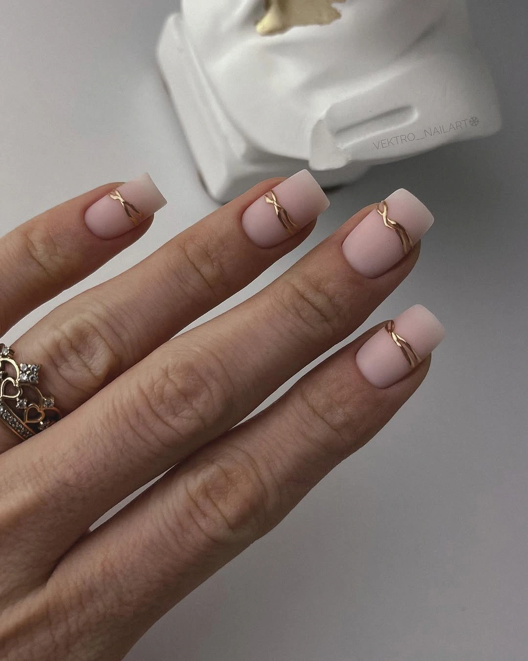 pale pink square nails with white tips and fine gold-looking arcs