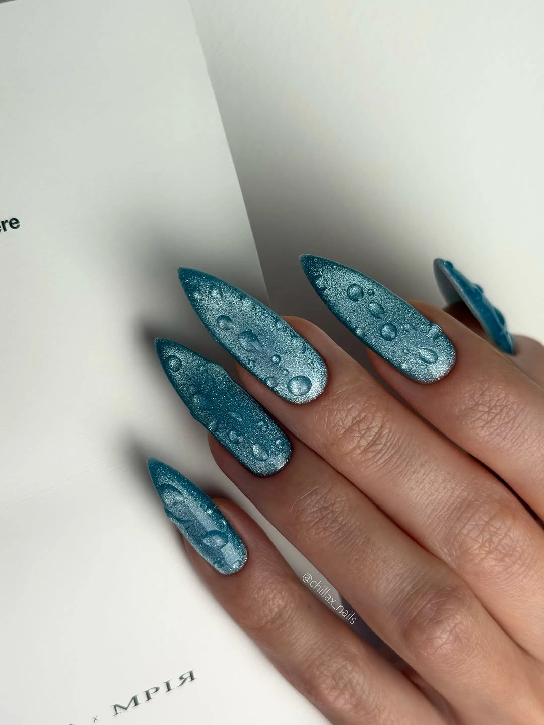 long teal almond nails with shimmer and pale droplet-like accents
