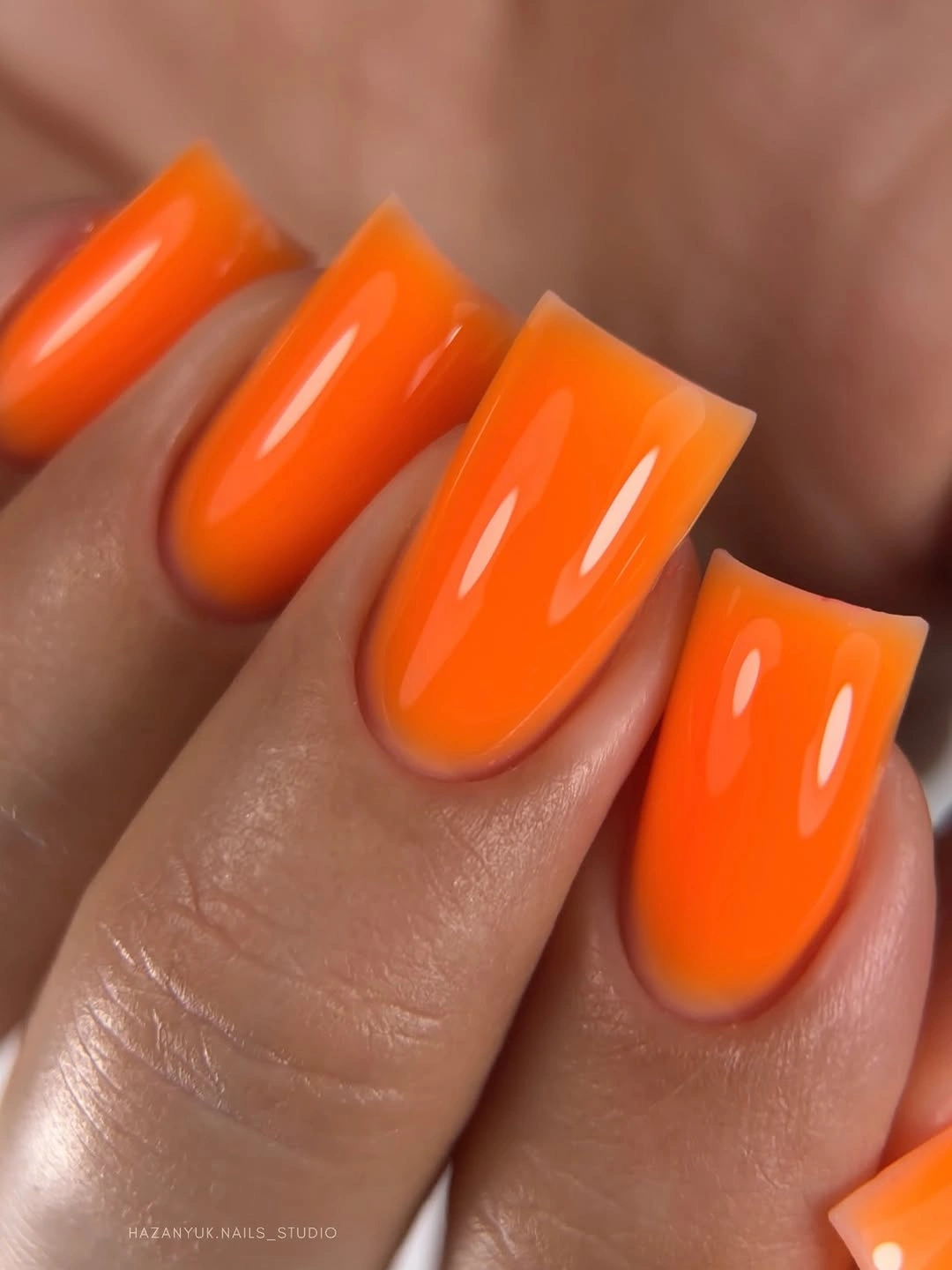 bright glossy orange nails on a medium-long square shape