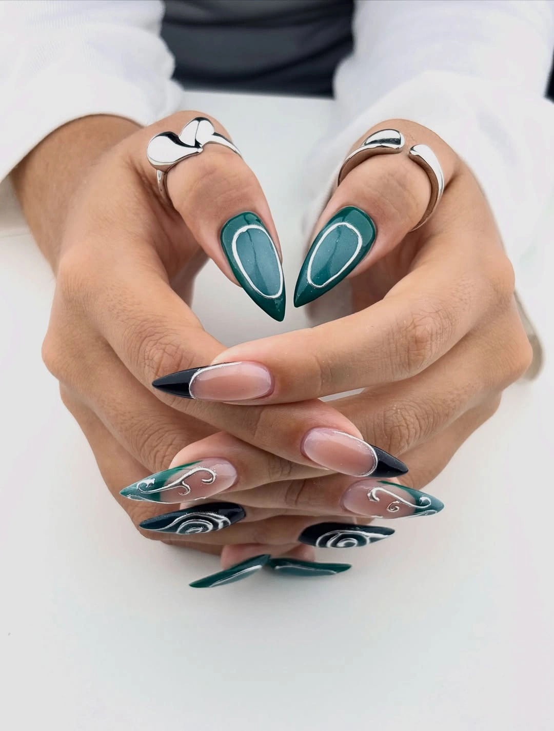 Long pointed nails with teal black tips and white swirls