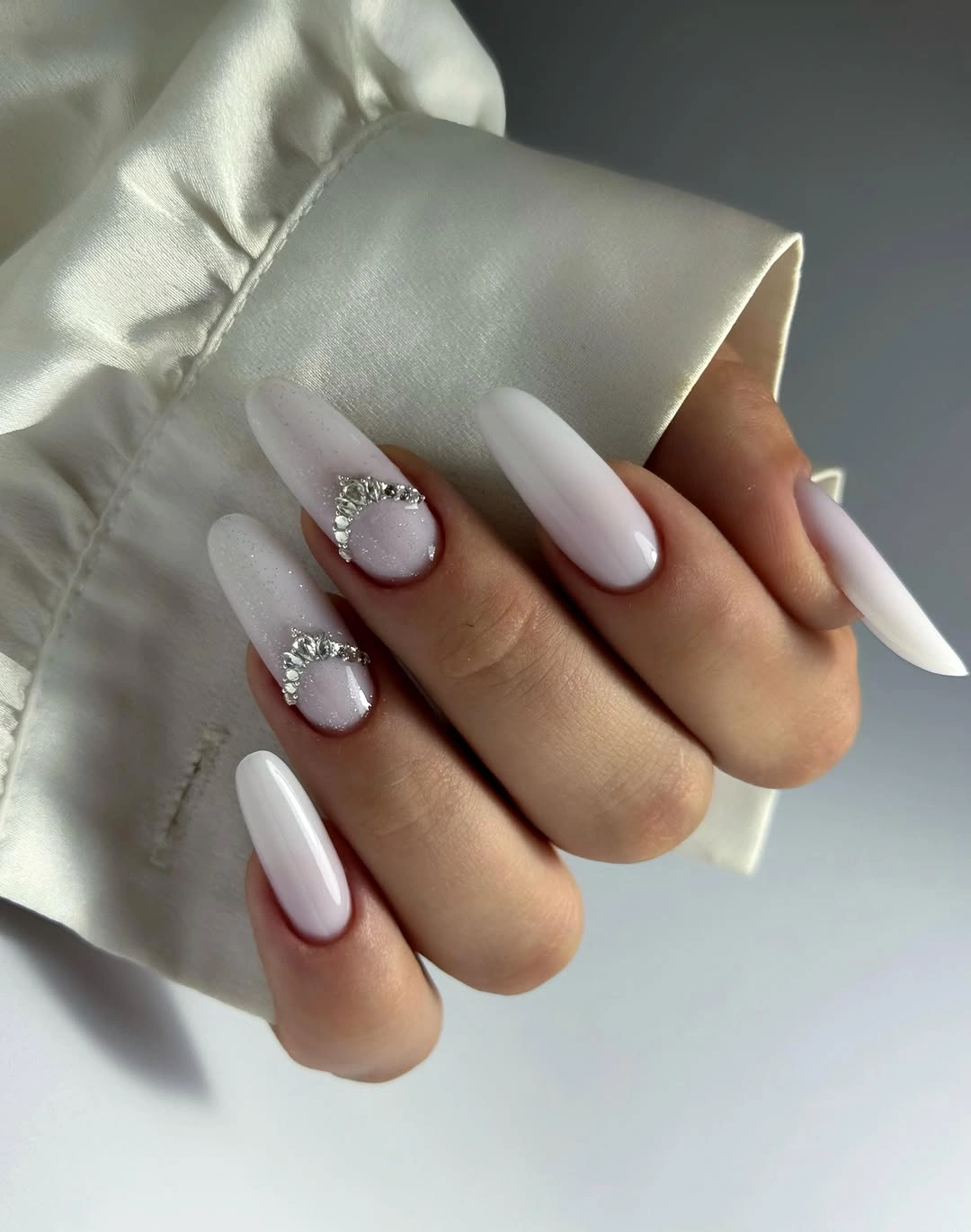 Milky white almond nails with small silver curved accents