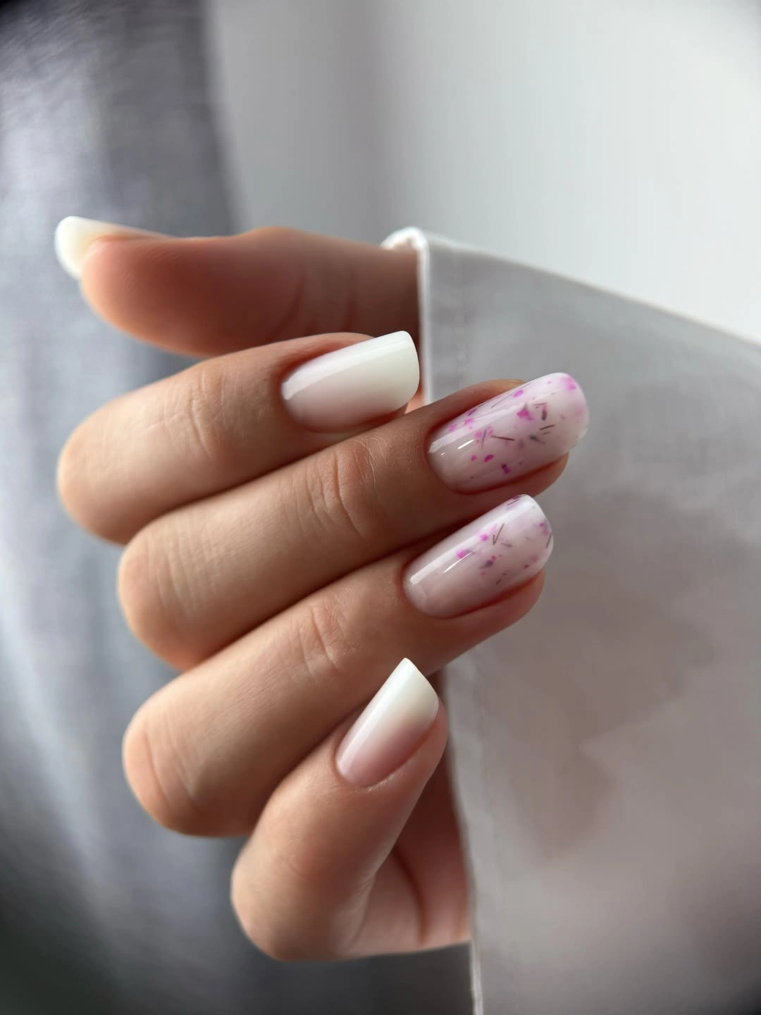 Creamy white rounded nails with pale pink confetti accents