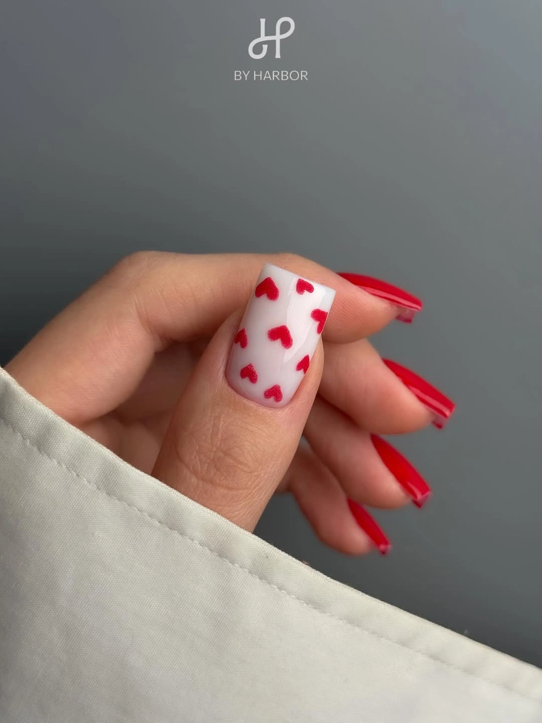 bright red square nails with one pale pink heart-like accent