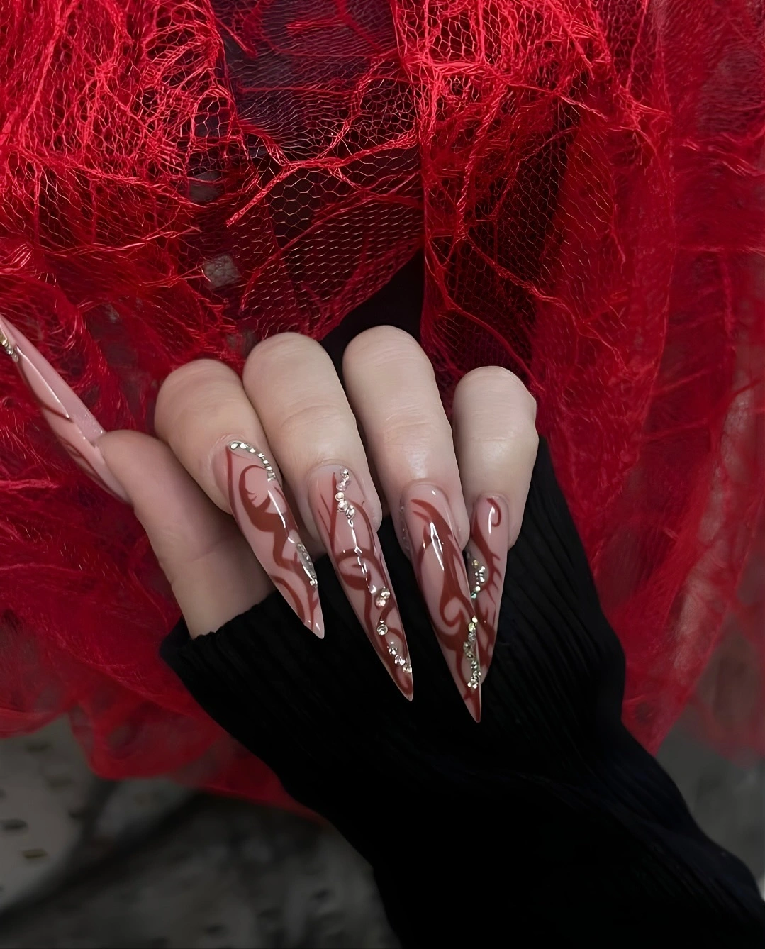 very long pale stiletto nails with red and pink flowing lines