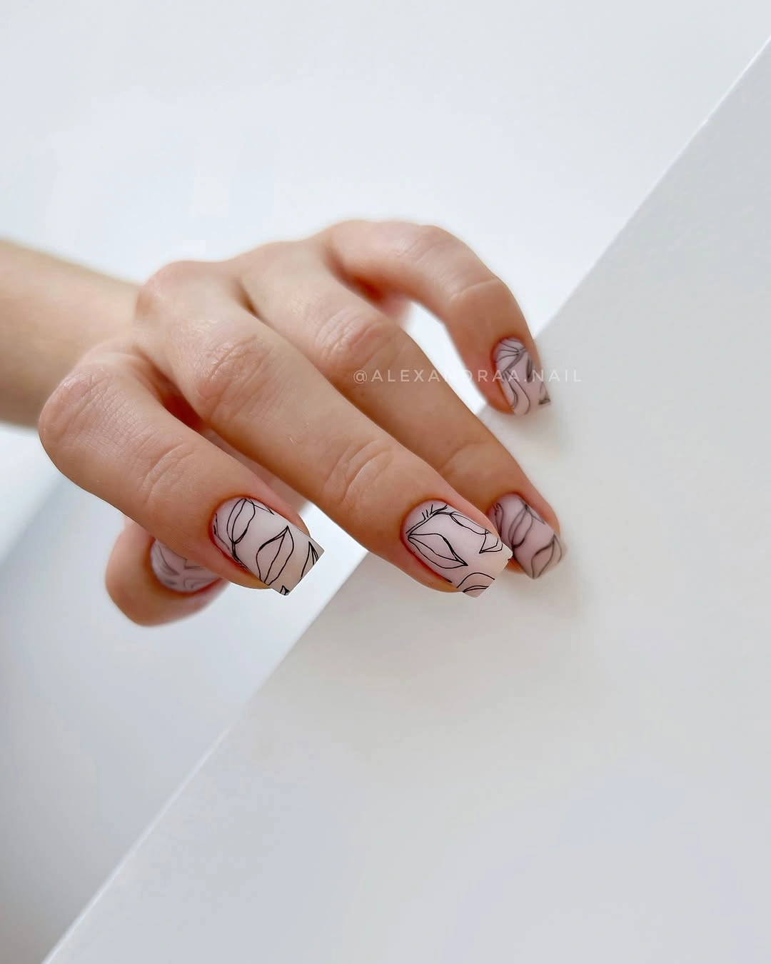 pale square nails with fine black abstract line-art accents