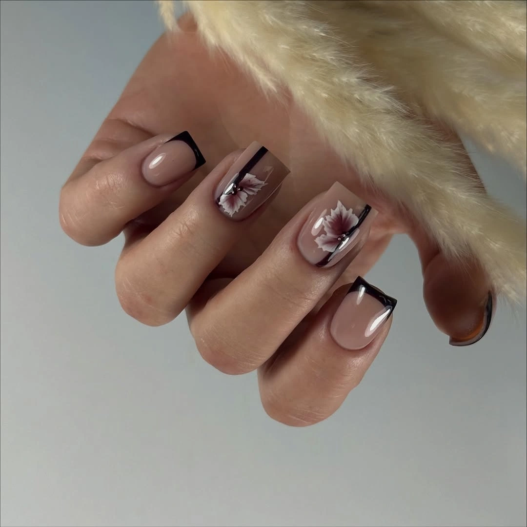nude almond nails with black edges and one pale floral accent