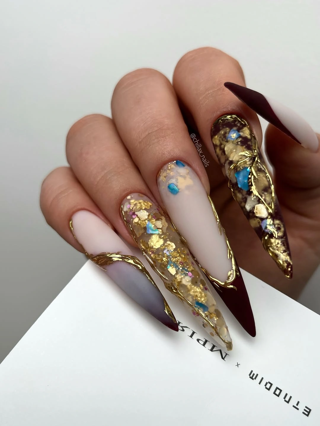 very long burgundy stiletto nails with one ornate bright accent