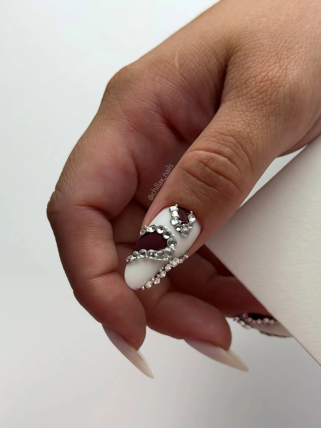 Long nude almond nails with concentrated silver crossing embellishment