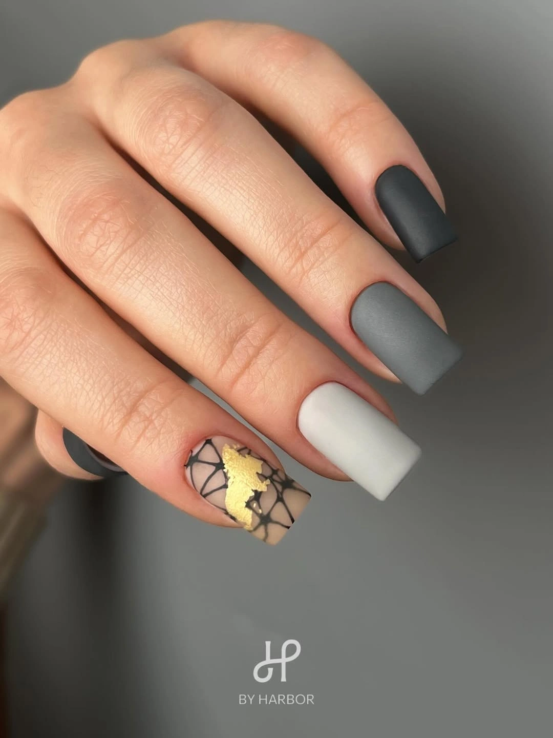 Matte black and white square nails with one gold veined accent