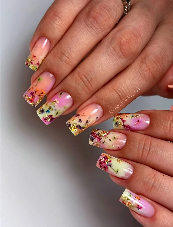 Short pink square nails with scattered colorful floral foil accents