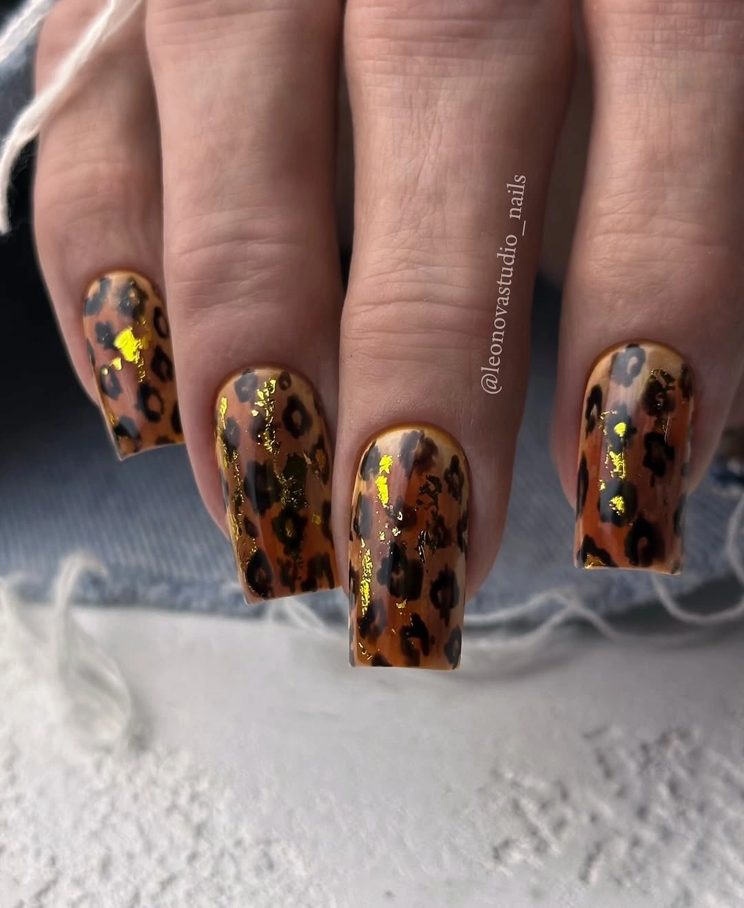 Warm amber square nails with dark spots and gold reflective flecks