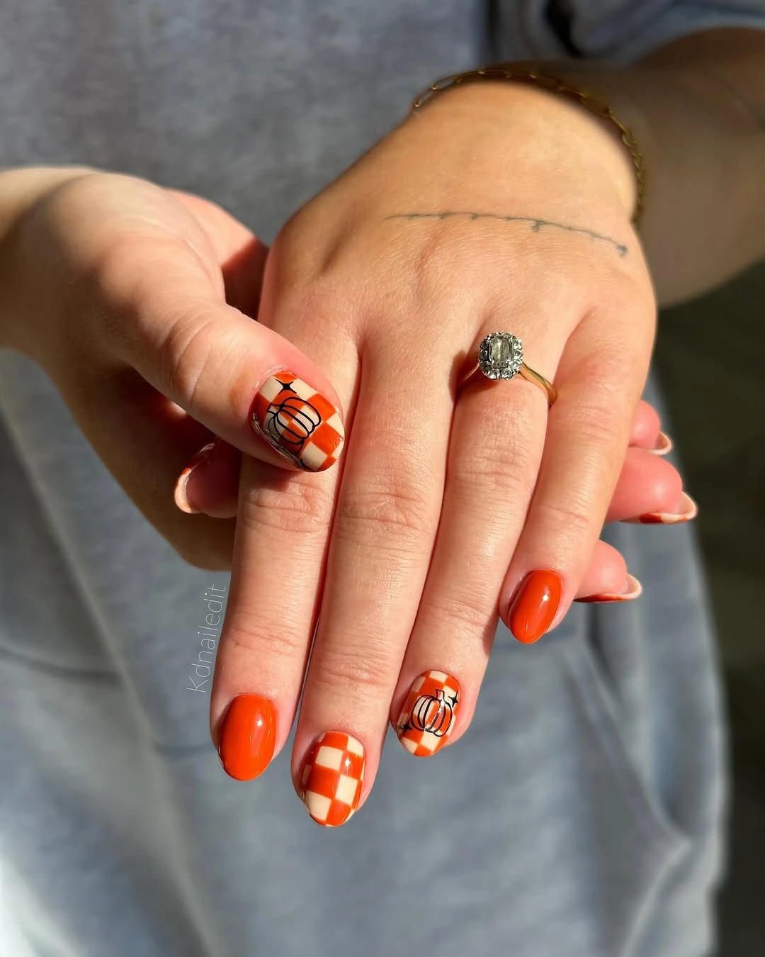 Short to medium orange and red checker fall nails with black and white pumpkin details