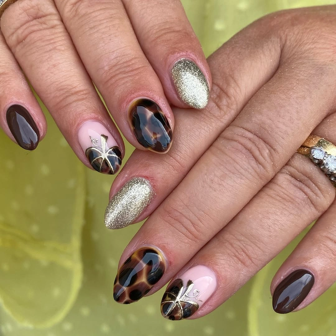 Brown plum and gold autumn nails with tortoiseshell or marble texture, glitter, and metallic details