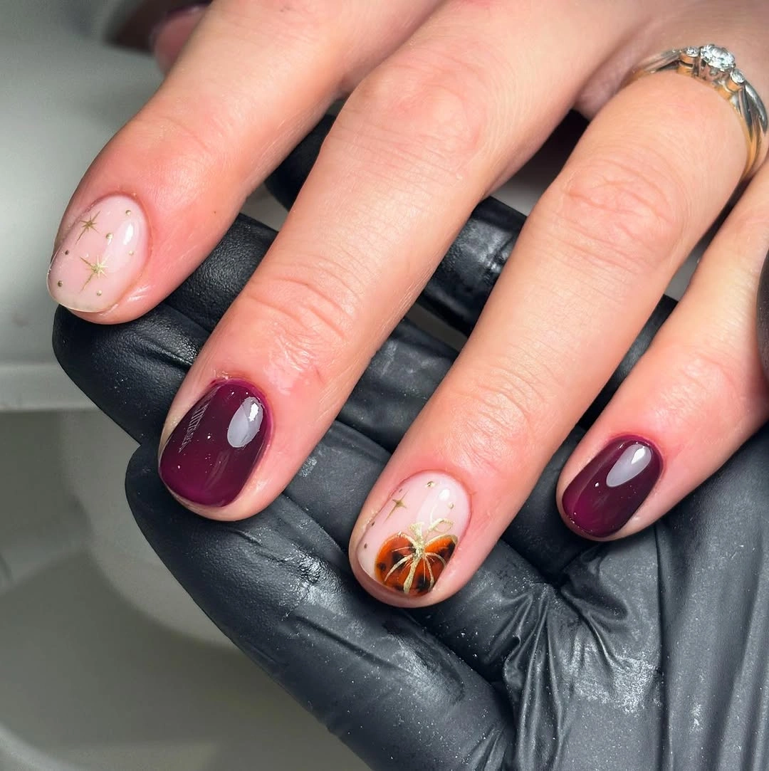 Short to medium pink and plum fall nails with one tiny orange pumpkin accent