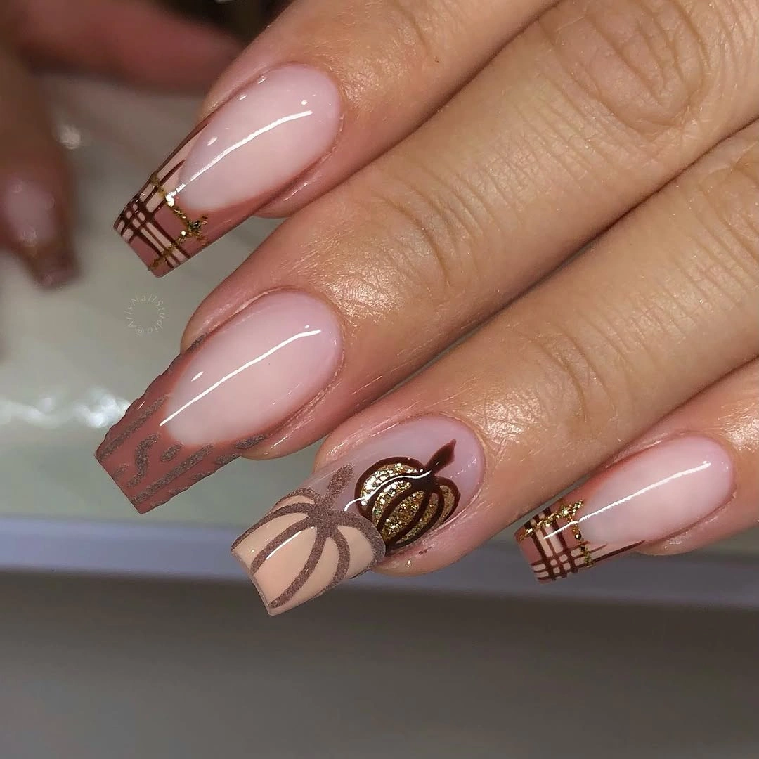 Long nude pink almond nails with brown plaid tips, seasonal linework, and pumpkin details