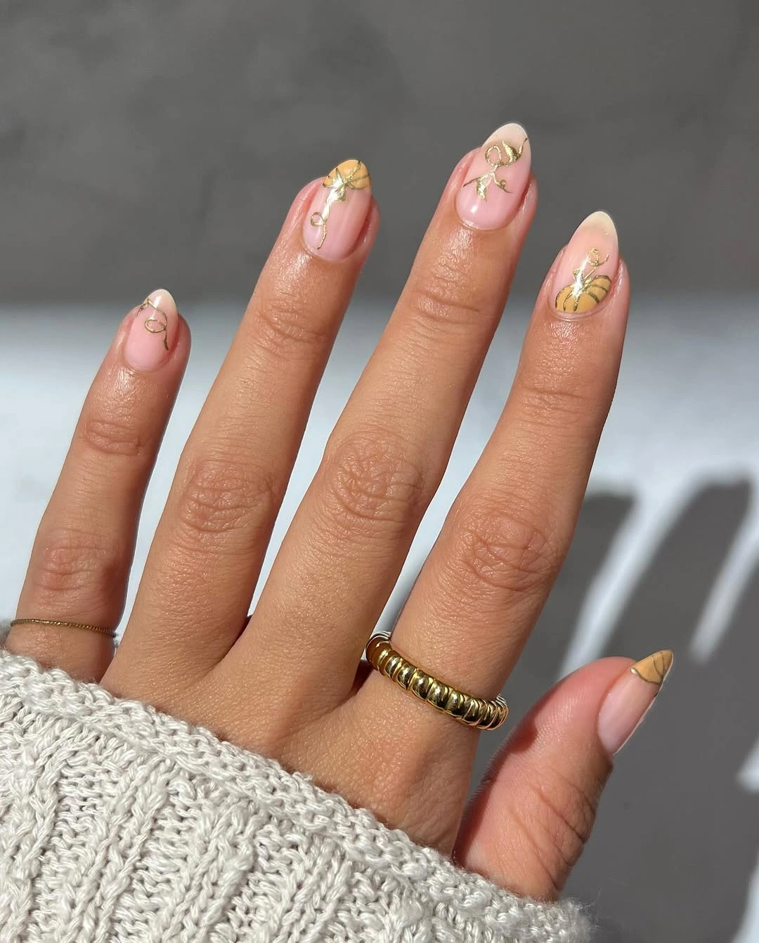 Short to medium soft pink fall nails with delicate gold pumpkin and autumn accents