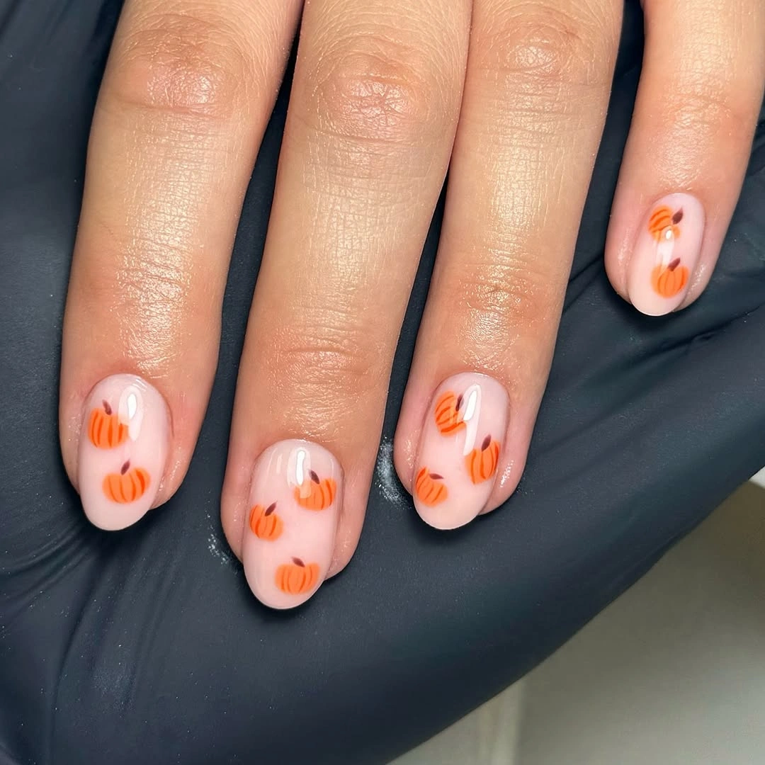 Short pale pink nails with clean orange pumpkin line accents for fall