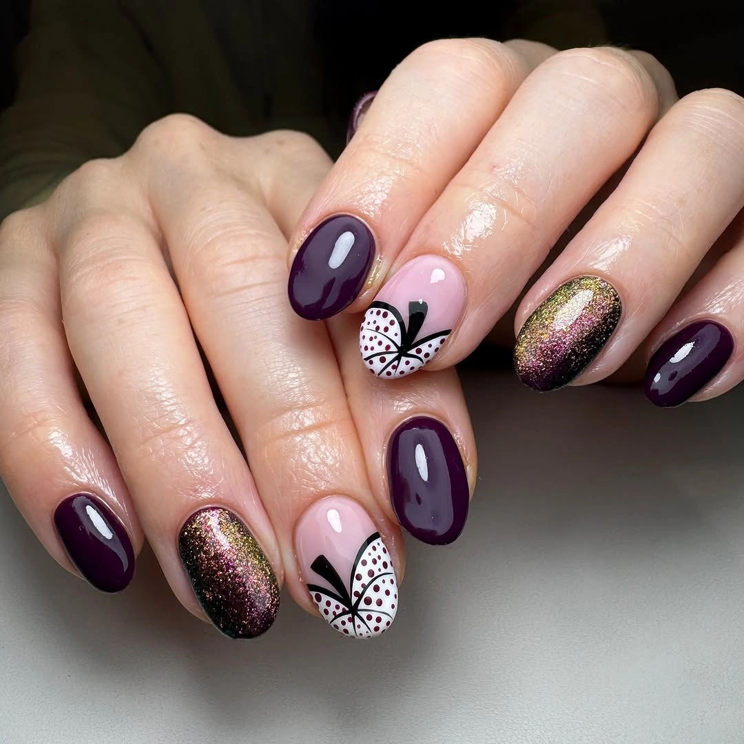 Dark plum fall nails with a pink accent, glitter, and black and white web detail