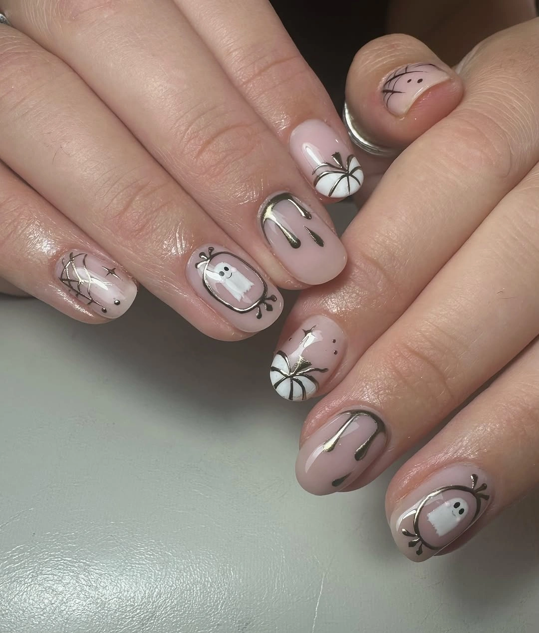 Short to medium nude fall nails with minimal black pumpkin and ghost line art