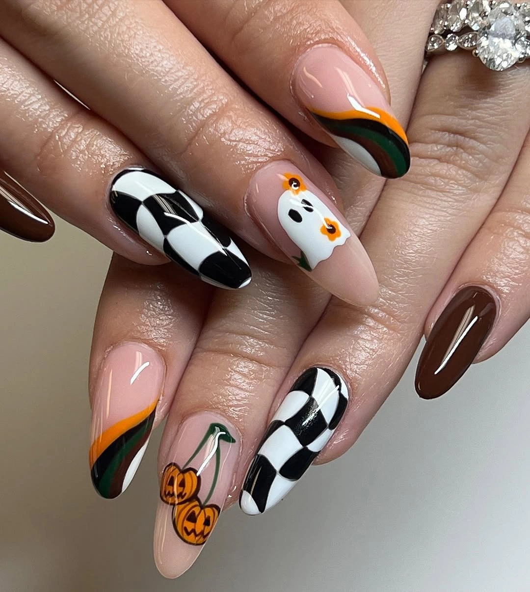 Pink fall nails with orange green and black pumpkins, jack-o-lanterns, and checker accents