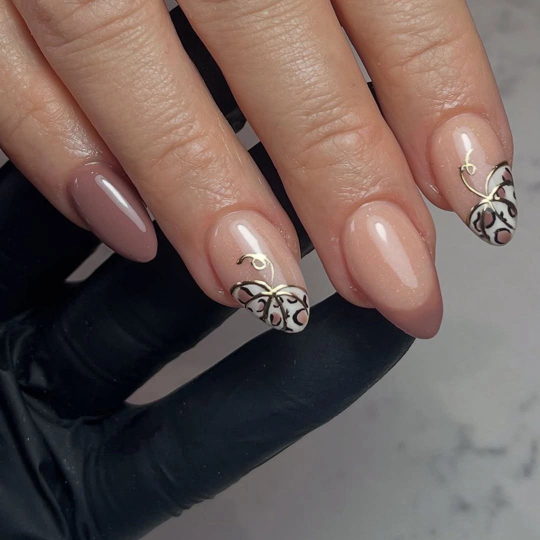 Nude pink almond fall nails with a black and white ornate accent detail
