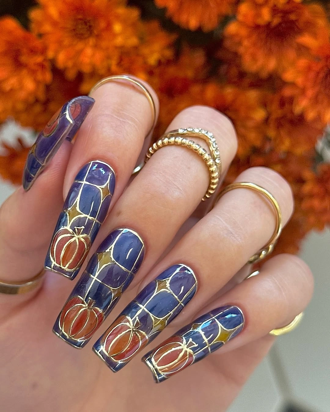 Long cobalt blue square coffin nails with gold pumpkin linework and a web-like grid