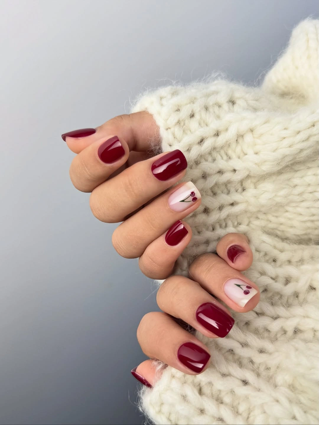 short burgundy nails with tiny cherry accents
