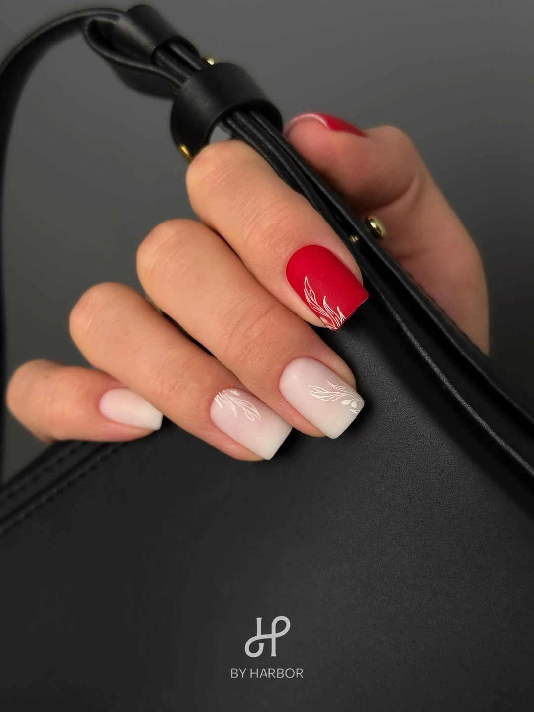 soft white nails with red accent and leaf art
