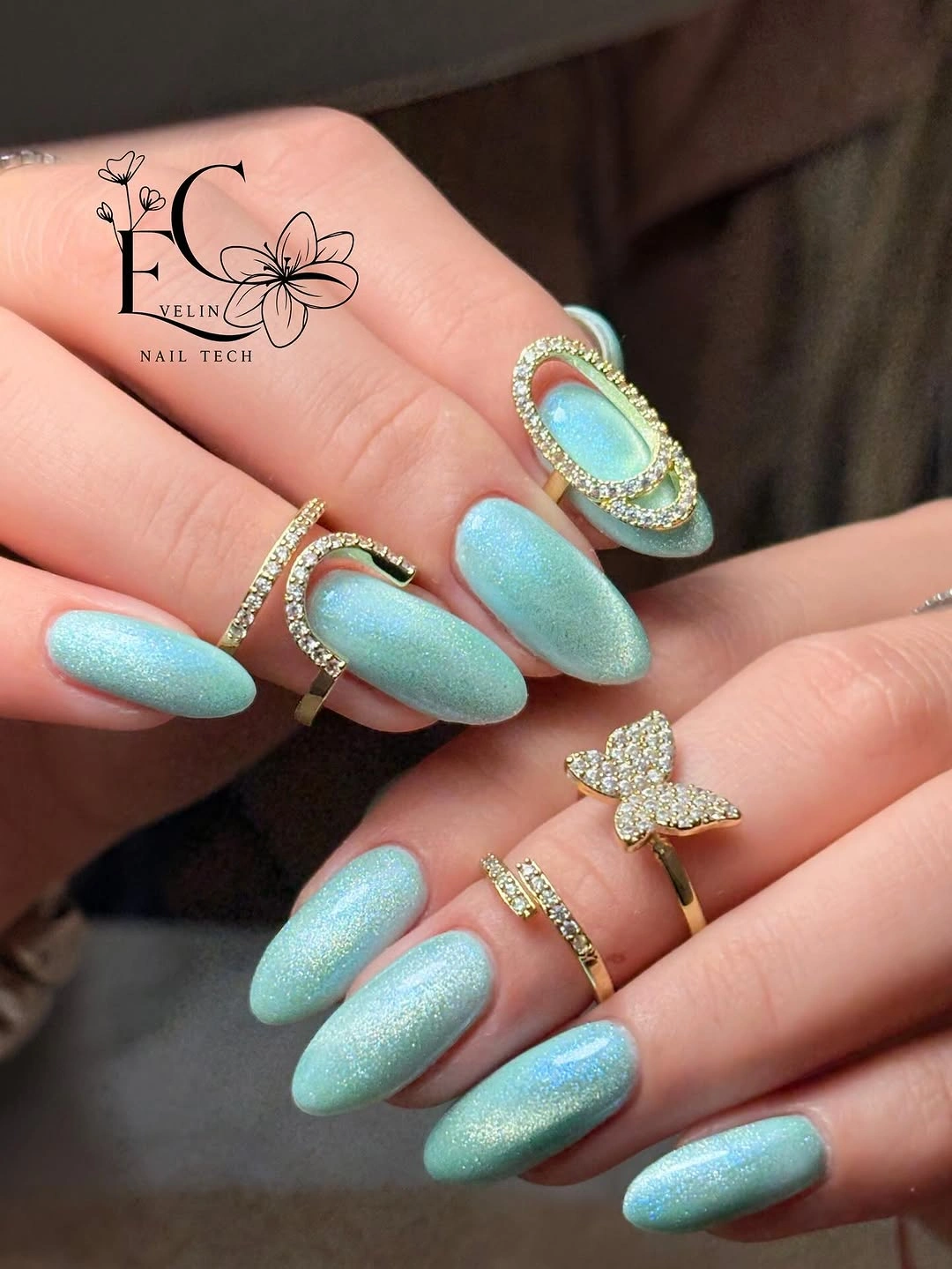 Bright turquoise almond nails with pearly texture and silver details
