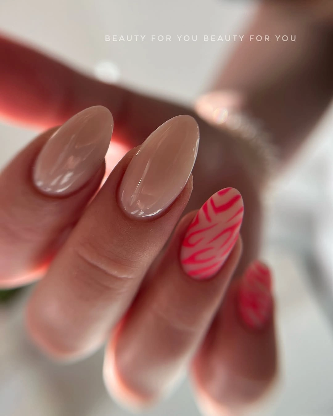 Sheer blush almond nails with curved red tips and swirls