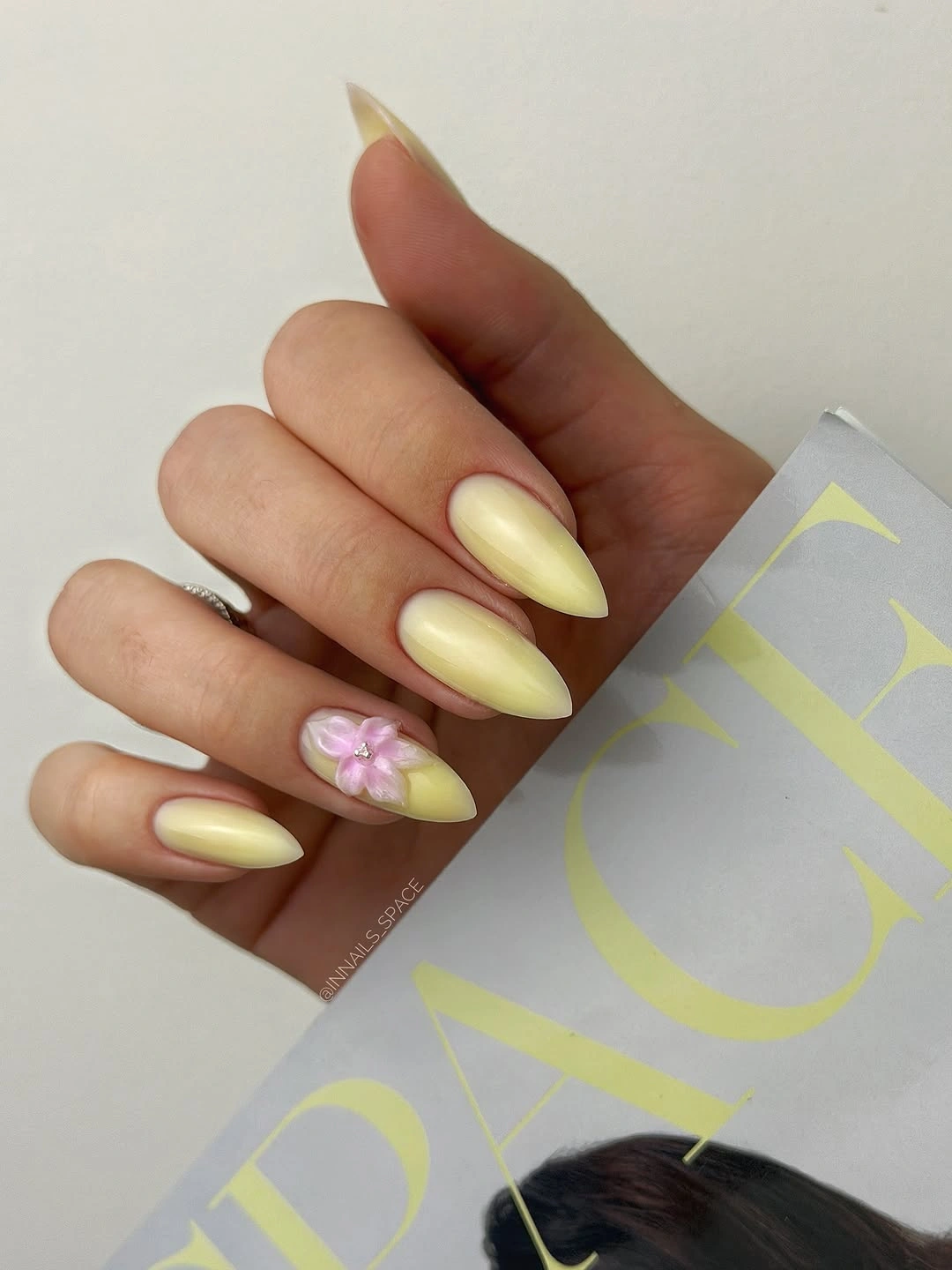 Pale yellow almond nails with one small pink flower accent