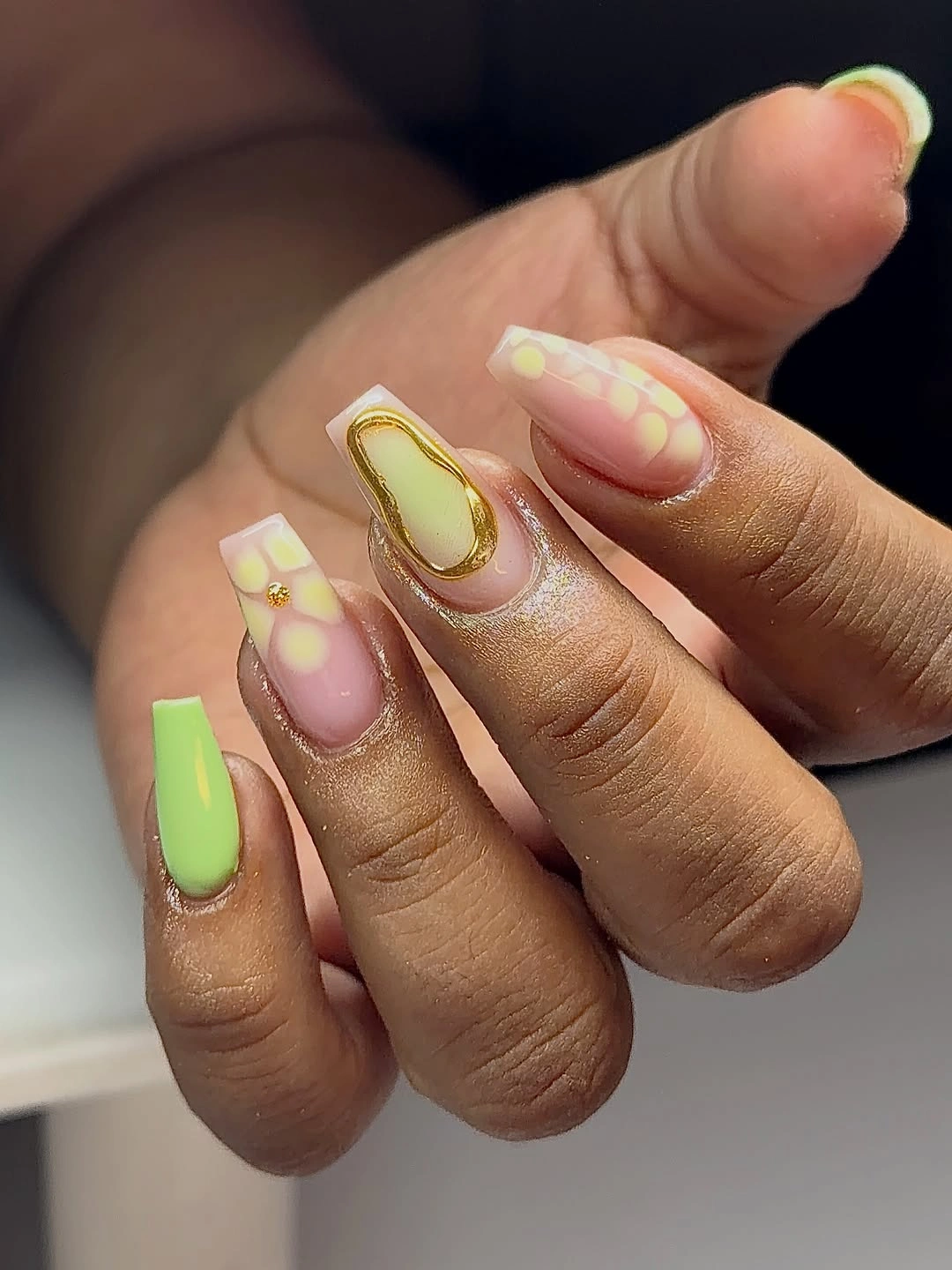 Short square nails with lime tips, pastel accents, and an outlined oval