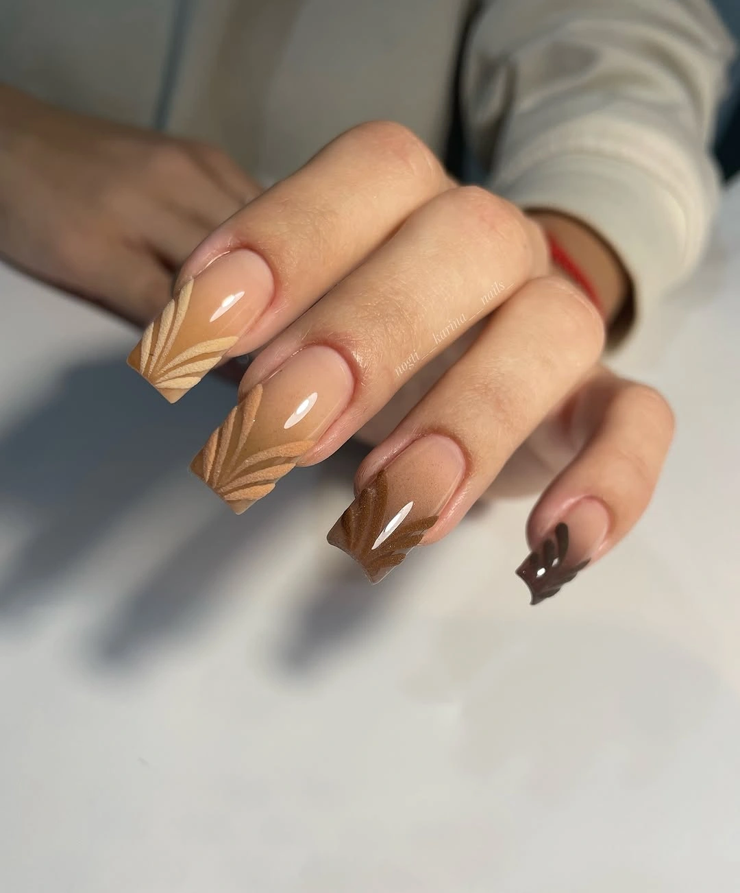 Medium square nude nails with angled brown geometric tips