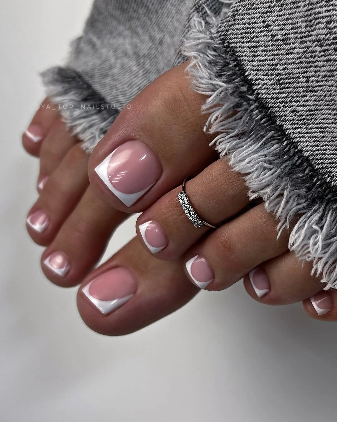 Short pale pink toenails with clean white French tips