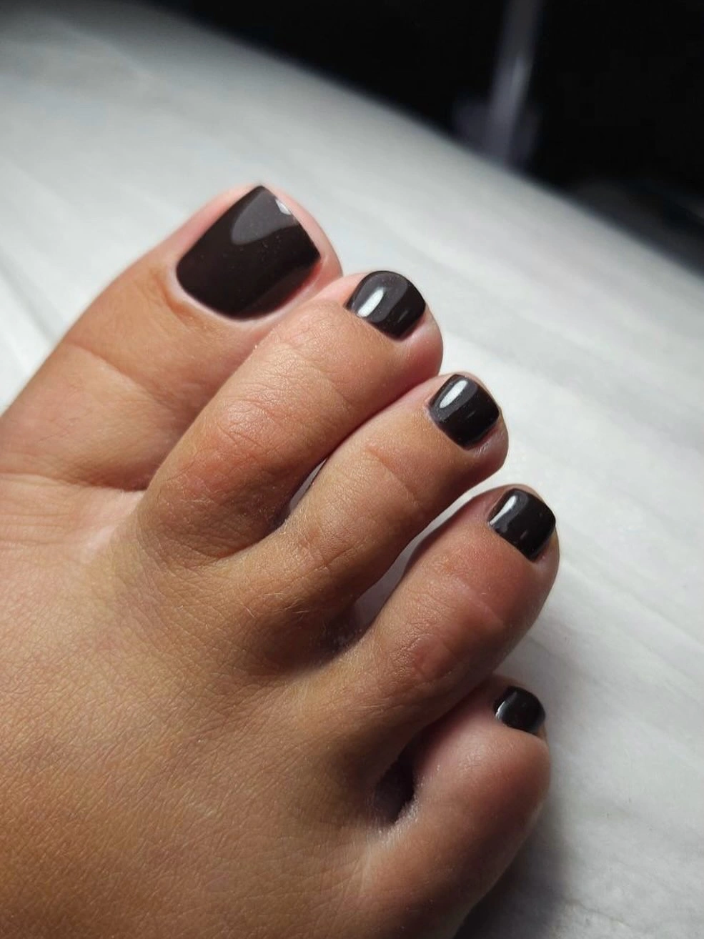 Short glossy black toenails with a clean square outline