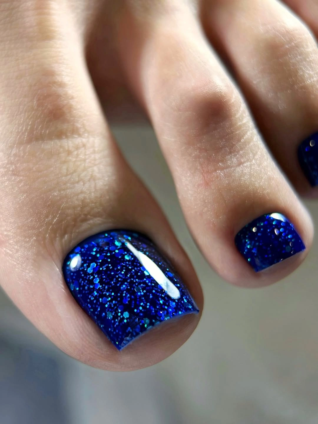 Short cobalt blue toenails with fine glitter on the big toe
