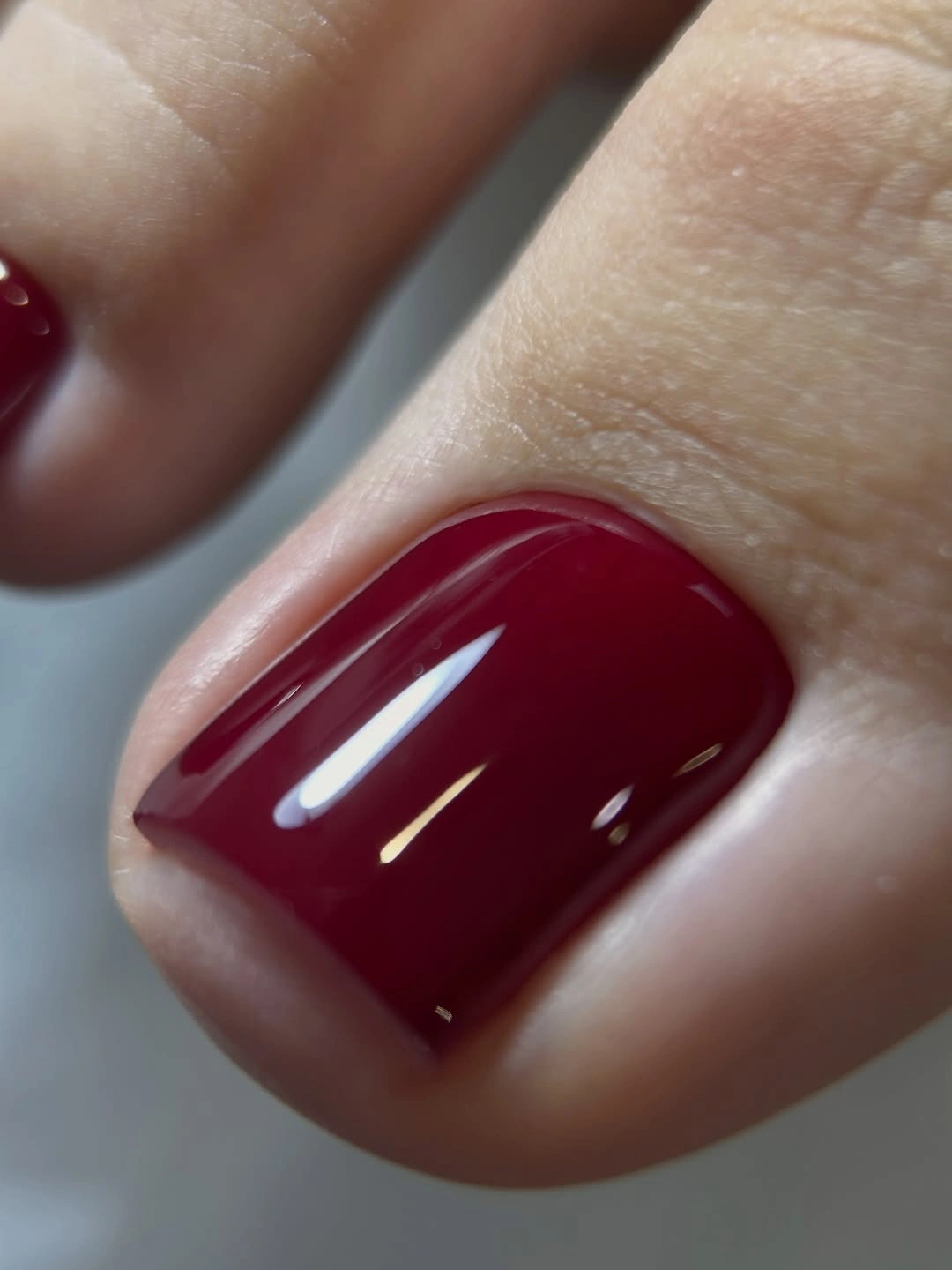 Close-up glossy cherry-wine big toenail with clean edges