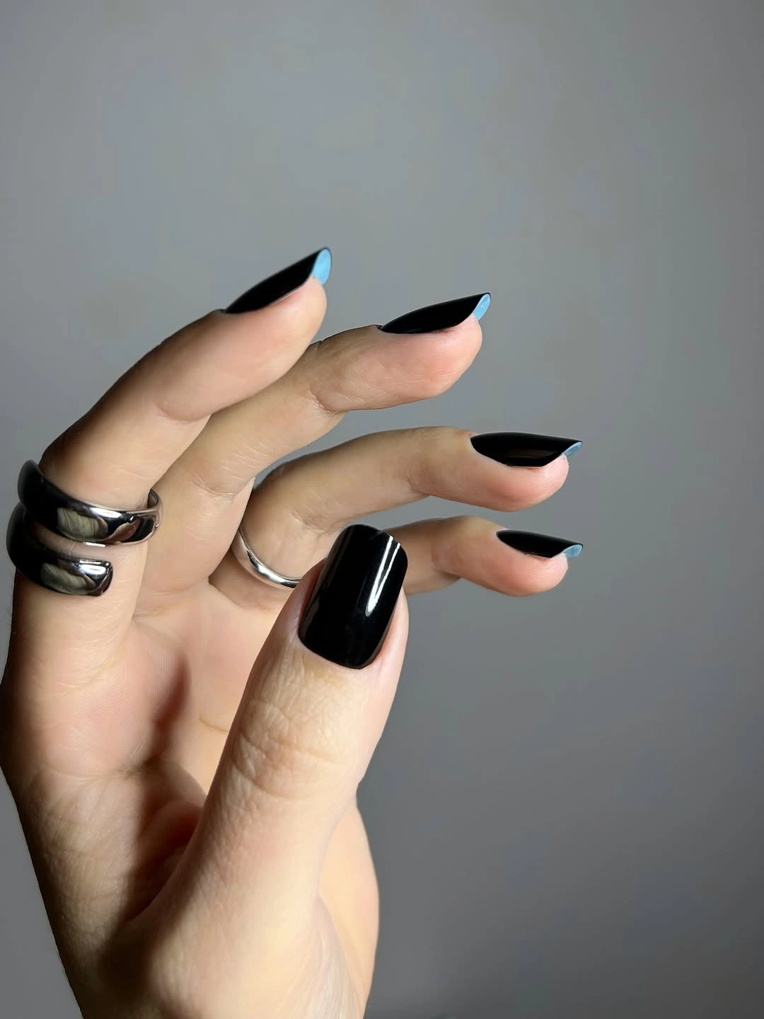 Glossy black almond nails with bright blue tip edges