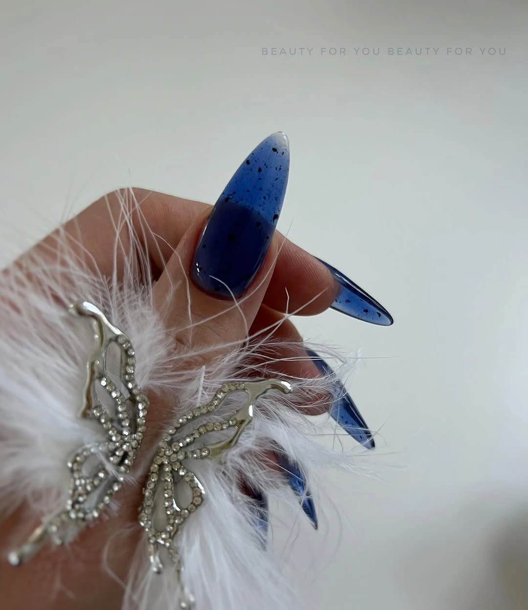 Long vivid blue almond nails with sparse dark speckles
