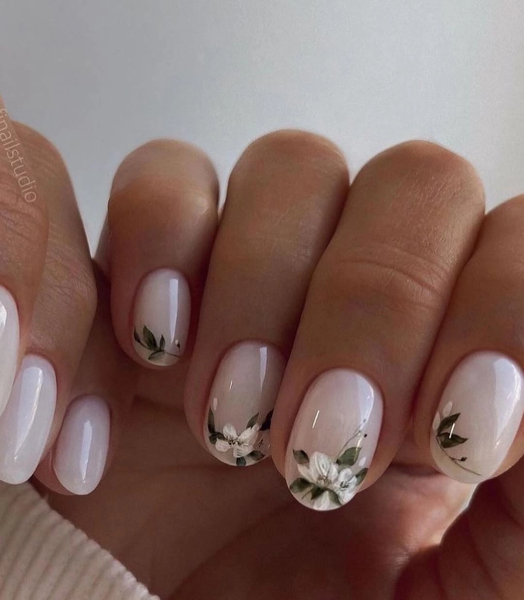 Short milky nails with white flowers and green leaves